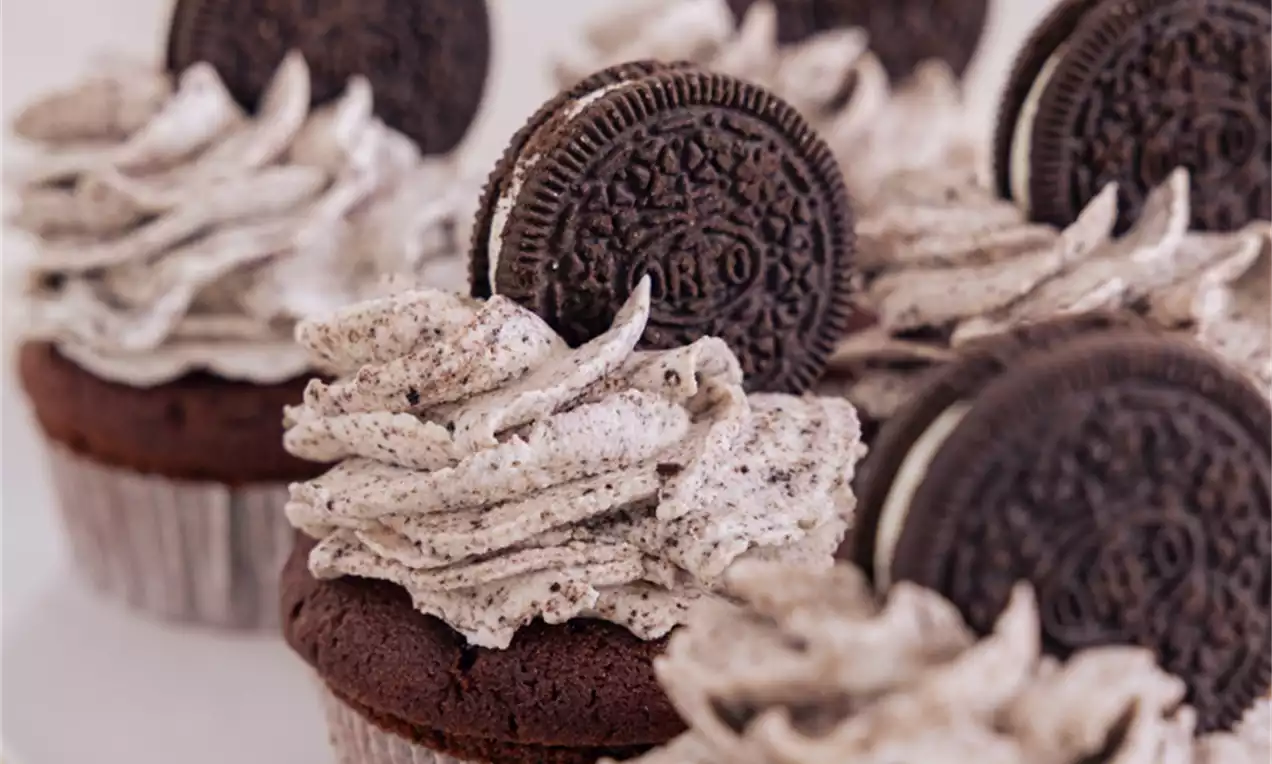Čokoladni kolački z rahlo hrustljavo Oreo podlago, puhasto pikčasto kremo v swirl obliki ter Oreo piškoti na vrhu, razporejeni na belem pladnju